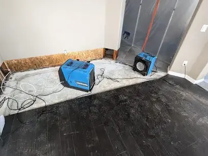 Air movers drying a floor inside plastic containment in Everett